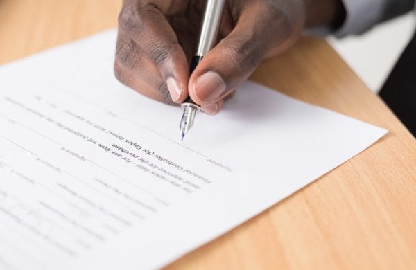 hand signing a contract with a pen