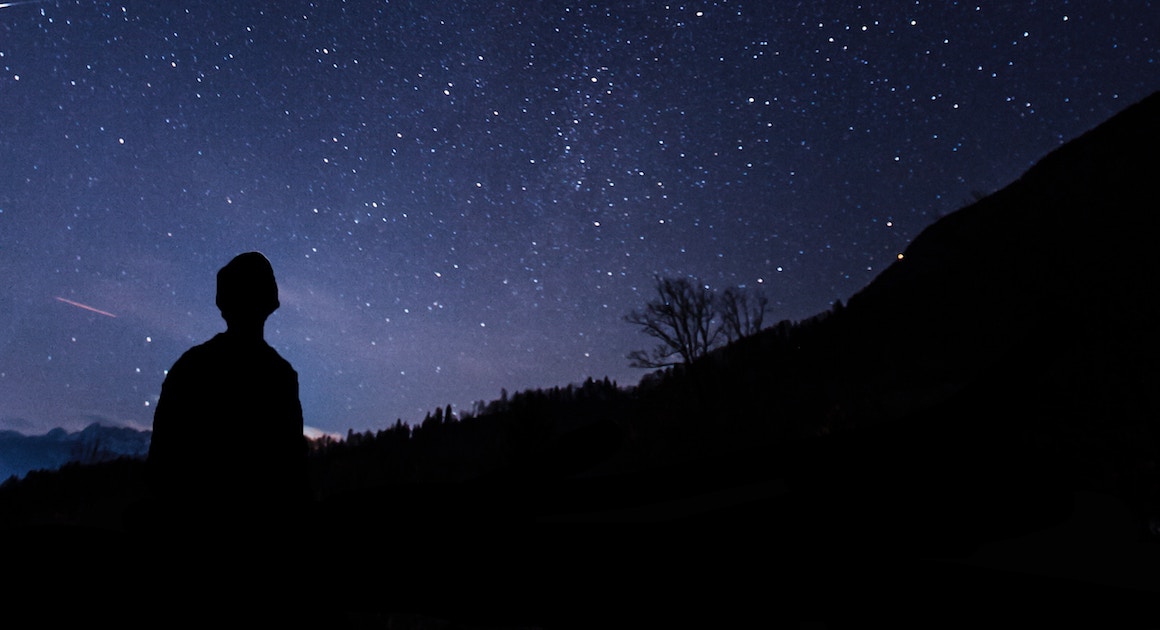 man in silhouette looking at the night sky