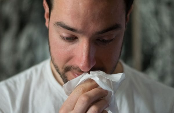 man wiping his nose with a tissue